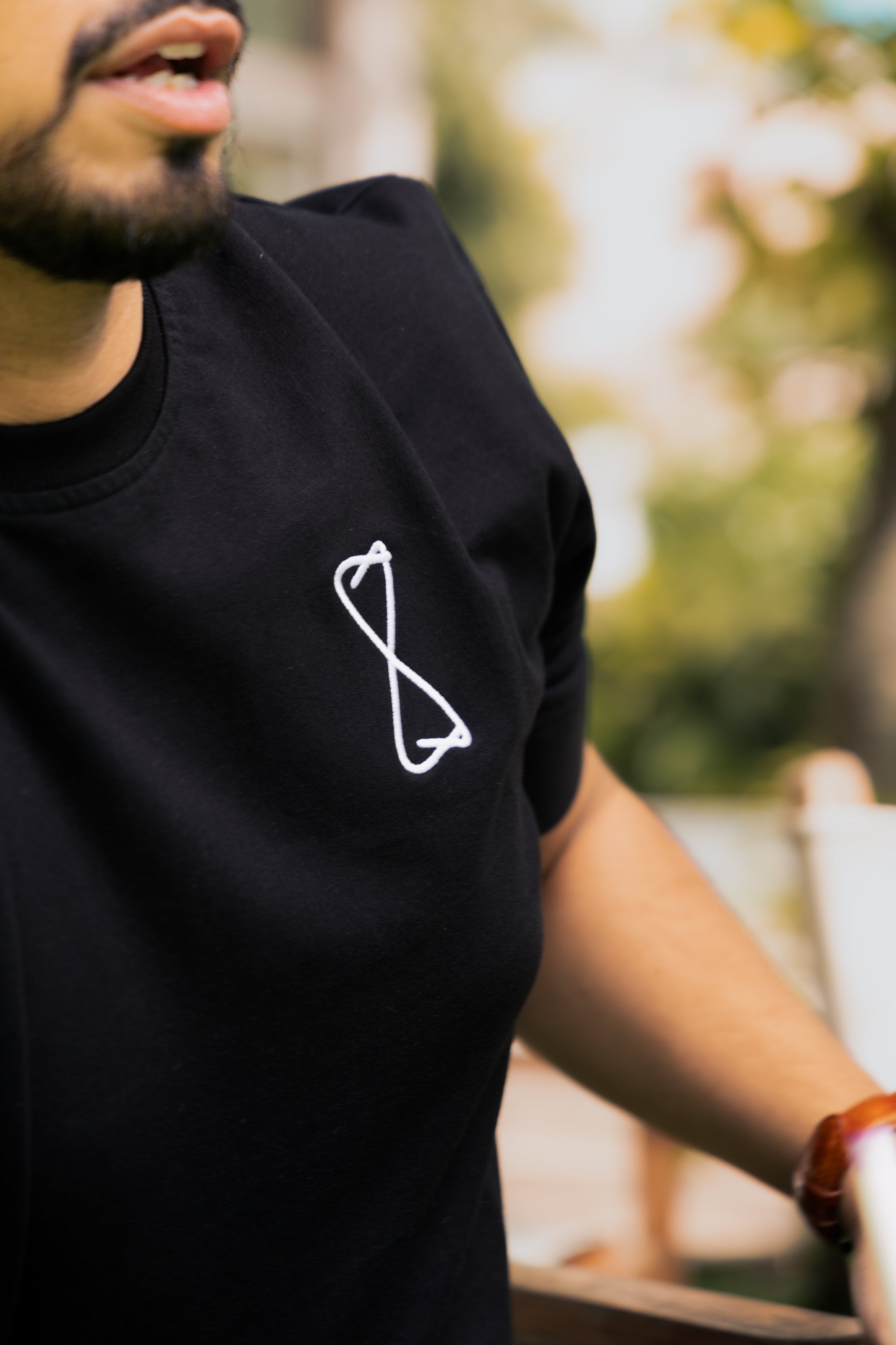 Person wearing a black t-shirt with a white logo outdoors