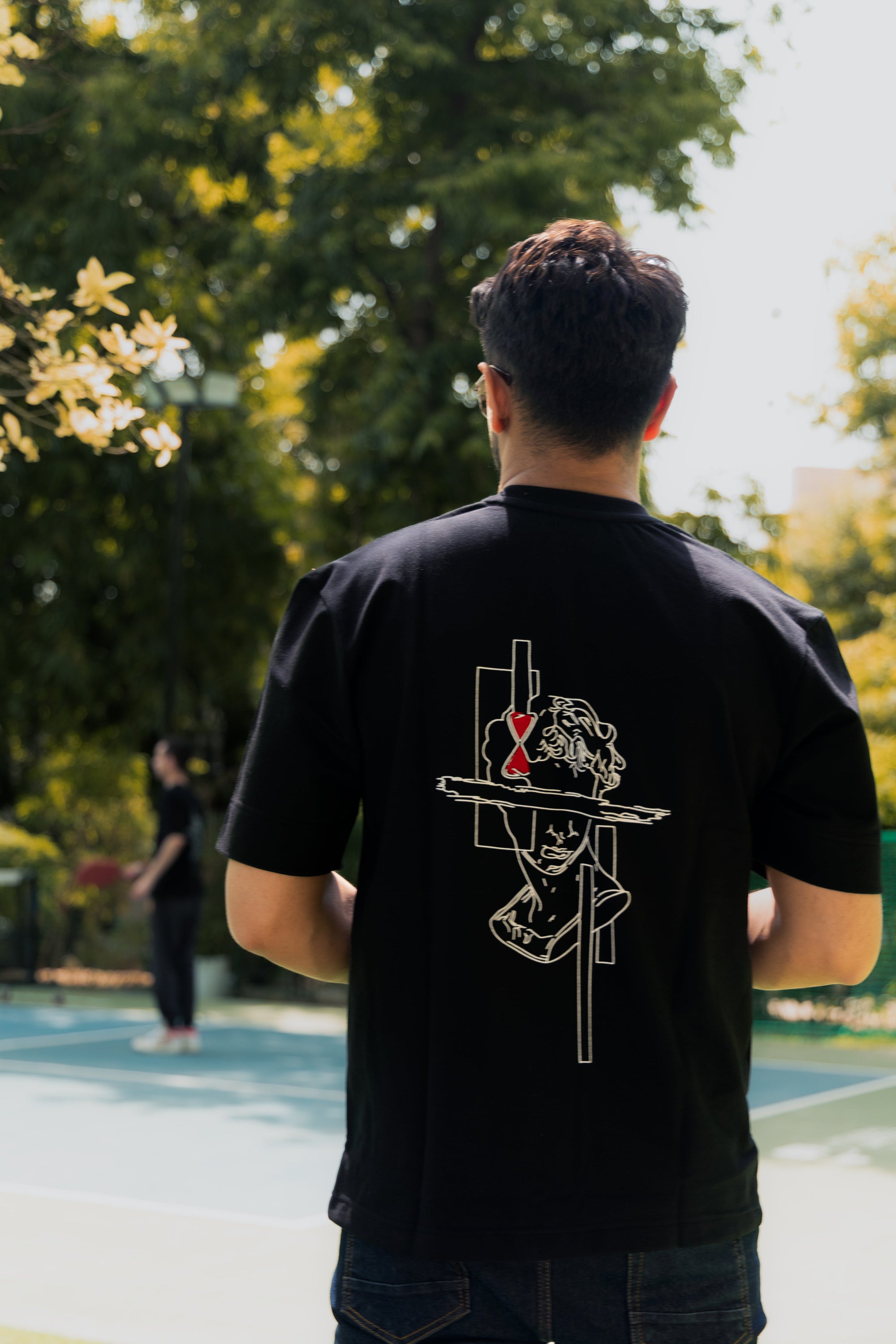 Person wearing a black t-shirt with a graphic design outdoors