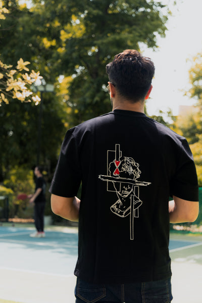 Person wearing a black t-shirt with a graphic design outdoors
